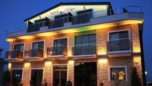 Un hotel de varios pisos con fachada de piedra, balcones y grandes ventanales.
