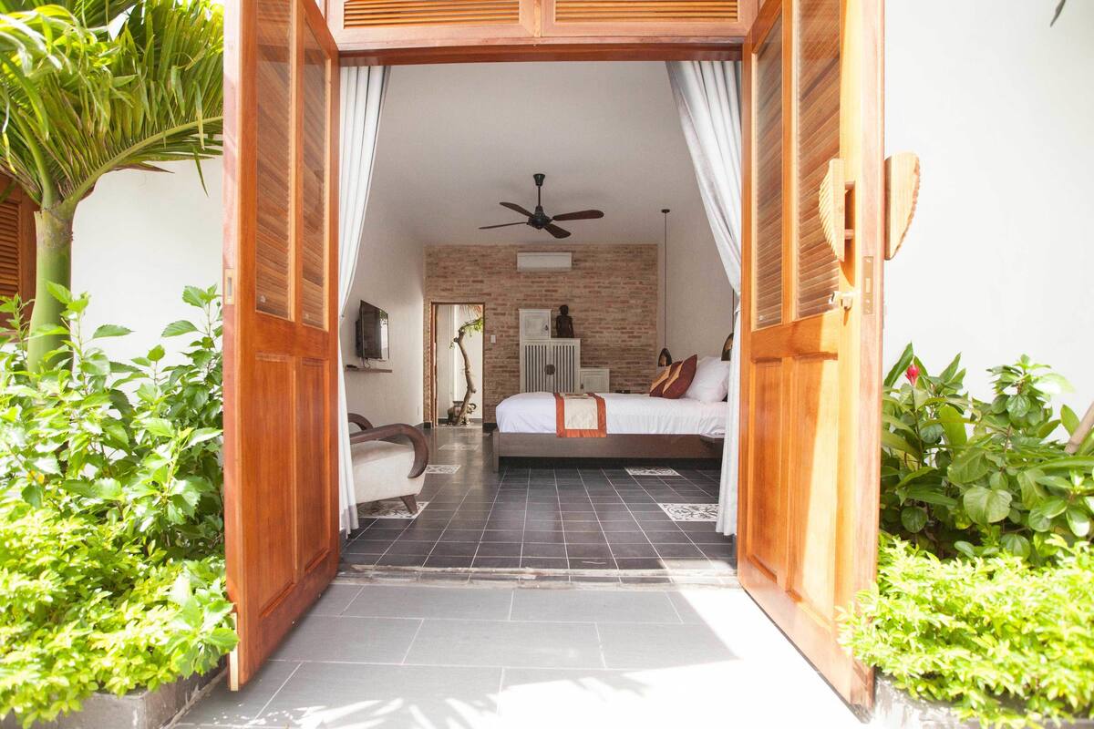 A bedroom with a bed, a ceiling fan, and a brick wall.