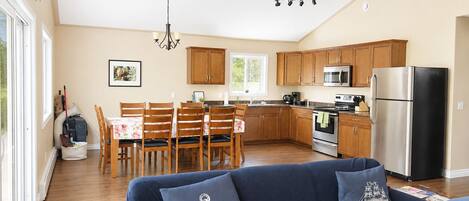 Una cocina moderna con armarios de madera, electrodomésticos de acero inoxidable y una zona de comedor con mesa y sillas.