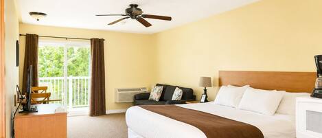 Habitación de hotel con cama, escritorio, silla, televisor y ventilador de techo.