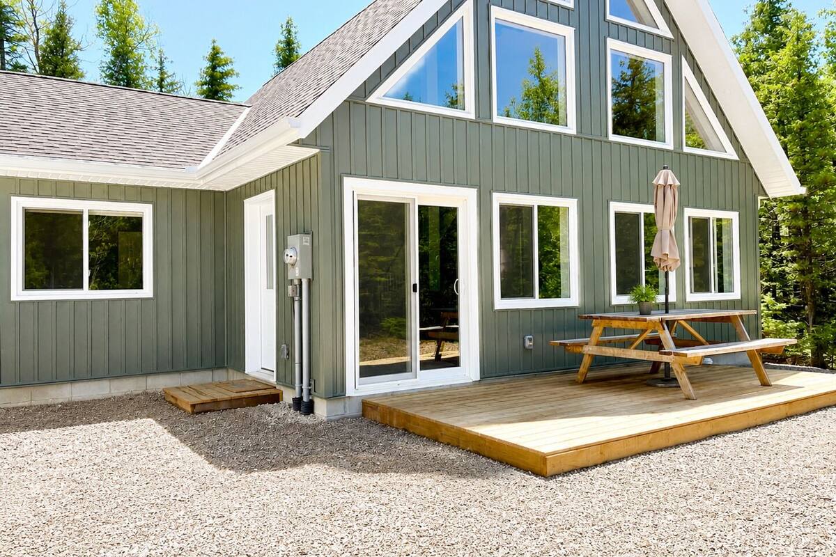 Une maison moderne dotée d’une terrasse, de grandes fenêtres et d’une prise de courant.