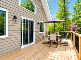 Una terraza con mesa y sillas, una puerta corrediza de vidrio y una pérgola con sombrilla.