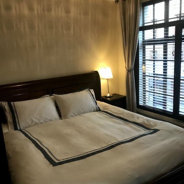 A hotel room with a large bed, a nightstand with a lamp, and a window with blinds. - Violet Lodge (Dublin)
