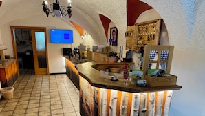 Un espace bar doté d’un comptoir en bois, d’un écran de télévision et d’une décoration rustique agrémentée de bûches de bouleau.