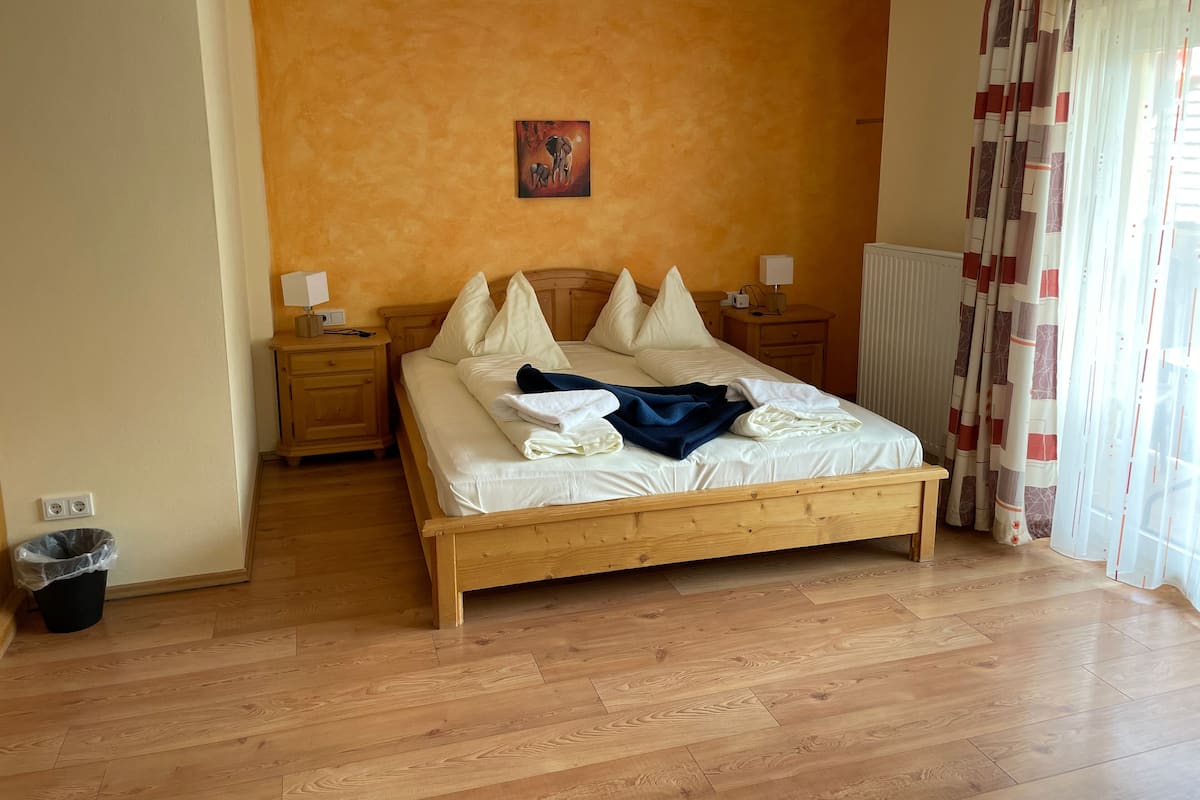 Une chambre à coucher avec un lit en bois, deux tables de chevet, un radiateur et un tableau accroché au mur.