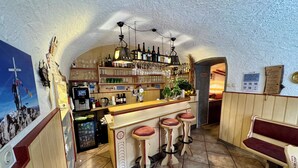 Un espace bar avec des tabourets, un comptoir et des étagères remplies de bouteilles et de verres.