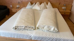 Un lit double avec une tête de lit en bois, deux tables de chevet avec des lampes et un canapé de couleur sombre.