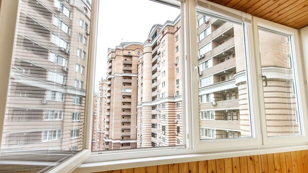 Une vue à travers une fenêtre d’un immeuble à plusieurs étages, doté de balcons et d’un plafond en bois.