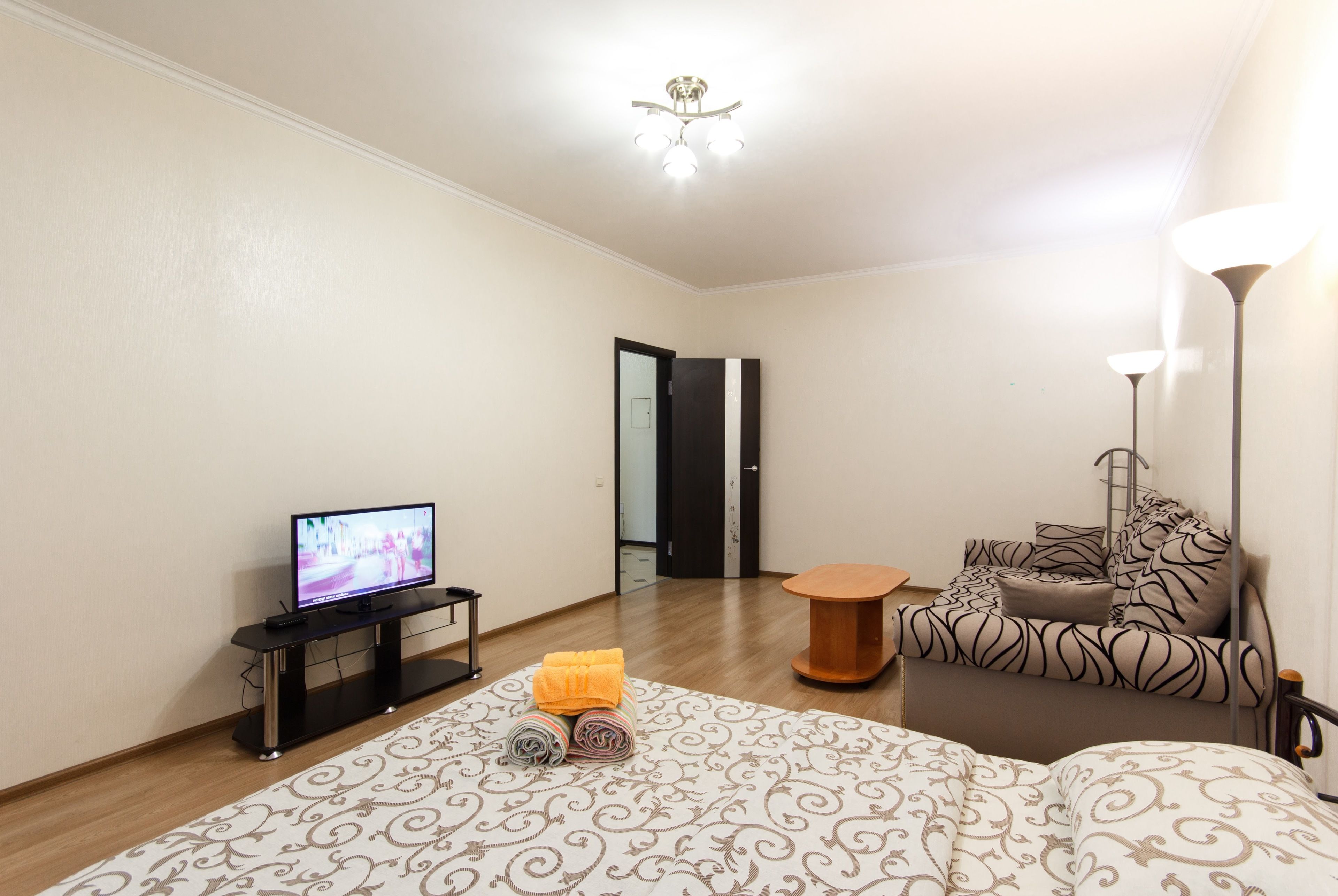 Une chambre d’hôtel avec un lit, un téléviseur posé sur un meuble, une petite table et une lampe.