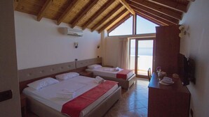 Habitació d'hotel amb dos llits, un sostre de fusta, una finestra gran i un escriptori amb un ram.