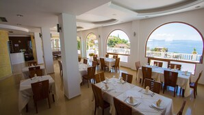 Un restaurant amb taules preparades per dinar, grans finestres amb vistes i un interior net i modern.