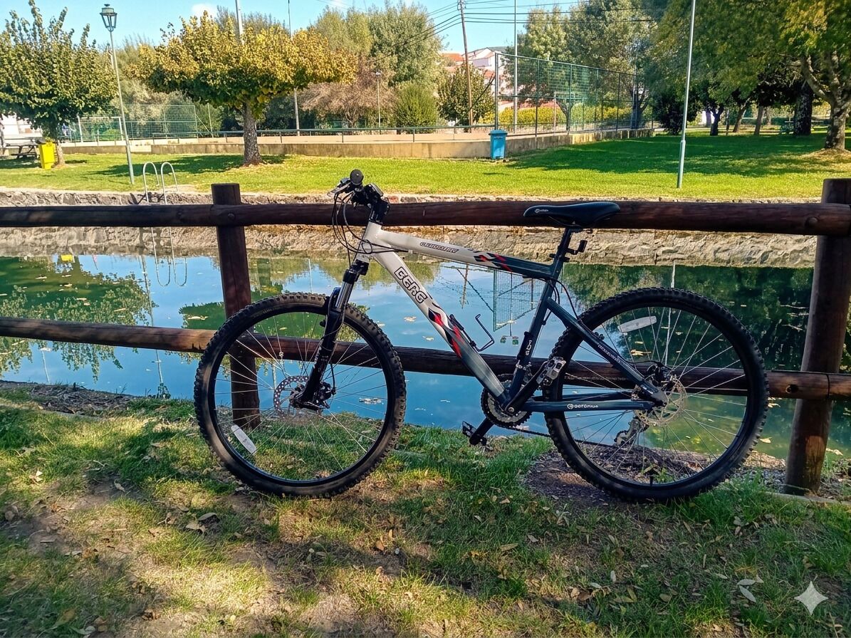 Una bicicleta estacionada cerca de una valla de madera, con un estanque al fondo.