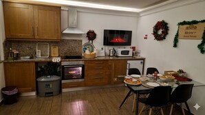 A kitchen with wooden cabinets, a microwave, an oven, and a dining area with a table and chairs. - Meimoa Guesthouse (Penamacor)