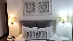 A bedroom with a bed, pillows, a bedside table, and wall-mounted lamps. - Meimoa Guesthouse (Penamacor)