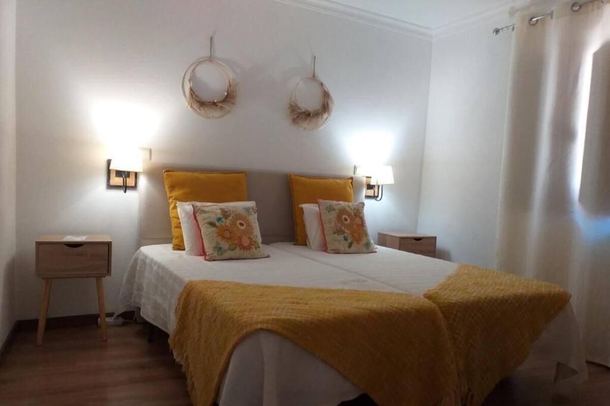 A bedroom with a bed, two bedside tables, a nightstand, and a wall-mounted lamp.