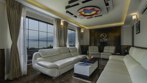 A modern living room with a white sofa, a coffee table, and a view of the outdoors. - Hotel Sarowar Pokhara-Luxury Hospitality in the Heart of Pokhara (Pokhara)
