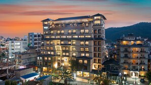 A multi-story hotel with balconies and a view of the surrounding cityscape at dusk. - Hotel Sarowar Pokhara-Luxury Hospitality in the Heart of Pokhara (Pokhara)
