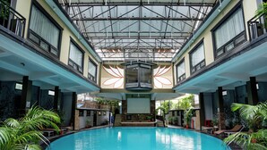 A large indoor swimming pool with a glass ceiling, surrounded by potted plants and lounge chairs. - Hotel Sarowar Pokhara-Luxury Hospitality in the Heart of Pokhara (Pokhara)