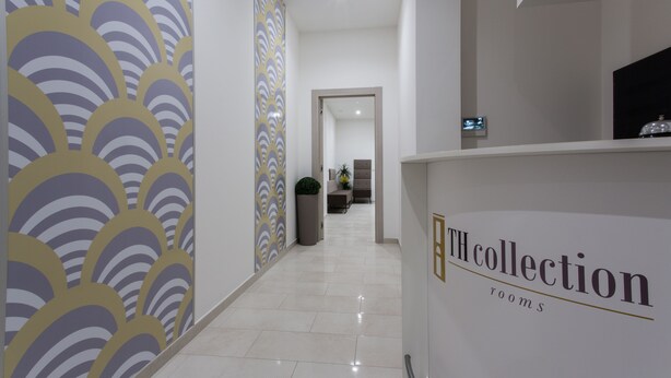 A hotel reception area with a modern design, featuring a reception desk labeled "The Collection rooms". - TH Collection Rooms (Oristano)