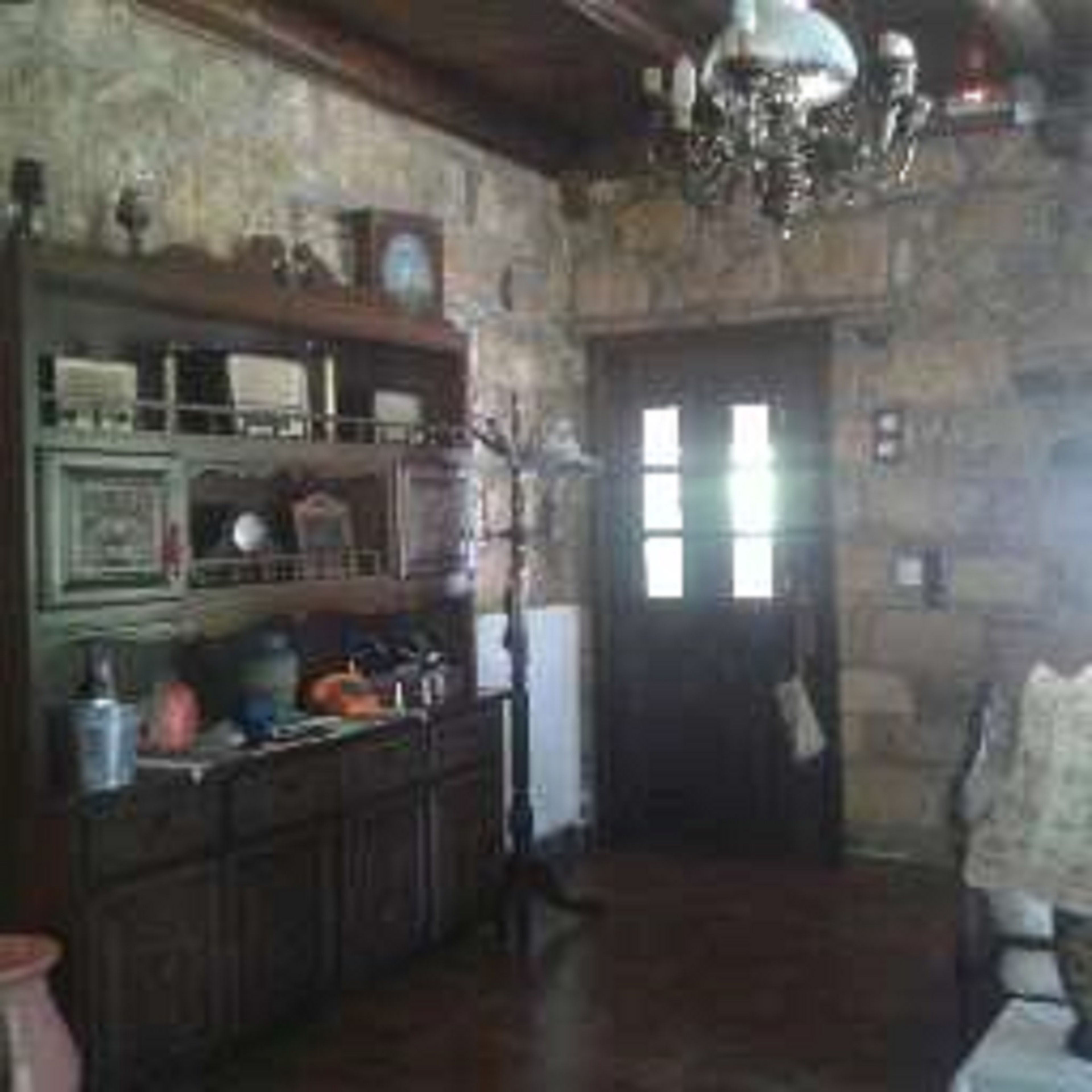 A rustic kitchen with wooden cabinets, a chandelier, and a stone wall.