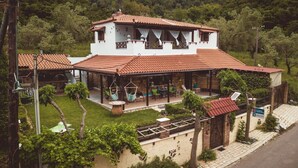 Uma casa de dois andares com um pátio, uma parede de pedra e um portão.