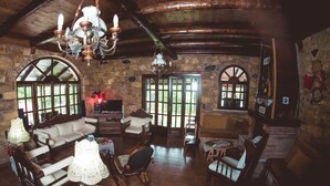 Um interior rústico com paredes de pedra, móveis de madeira e um lustre.