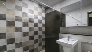 A modern bathroom with a checkered tile wall, a white sink, and a mirror above it. - G&G Hotel (Busan)