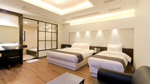 A modern hotel room with two beds, a large bathroom with a sink, and a sliding door closet. - G&G Hotel (Busan)