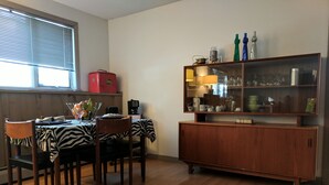 A dining area with a wooden table, chairs, and a zebra-patterned tablecloth. There is a cabinet with glass doors displaying various items.