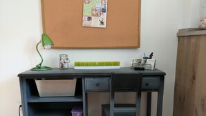 A desk with a corkboard, a lamp, and storage shelves.