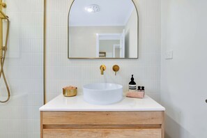 Une salle de bain avec un lavabo blanc, des robinets dorés et un meuble-lavabo en bois.