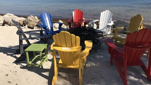 A beach setting with a fire pit surrounded by colorful Adirondack chairs. - Penthouse Apartment Sunsets in Key Largo, Kawama Yacht Club Tower (Key Largo)