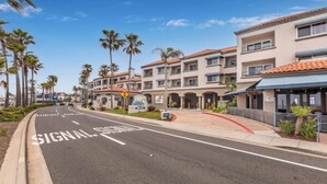 A multi-story hotel with a central courtyard, palm trees, and a clear sky. - Visit The Tamarack Beach Resort! Awesome Beach View! (Carlsbad)