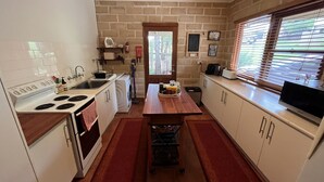 Une petite cuisine équipée d’une cuisinière, d’un évier et d’une table en bois, agrémentée d’un tapis rouge.
