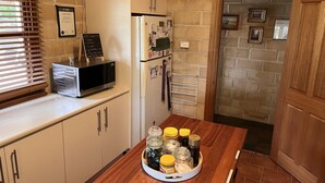 Une cuisine compacte équipée d’un four à micro-ondes, d’un réfrigérateur et d’une table en bois sur laquelle sont posés des bocaux.
