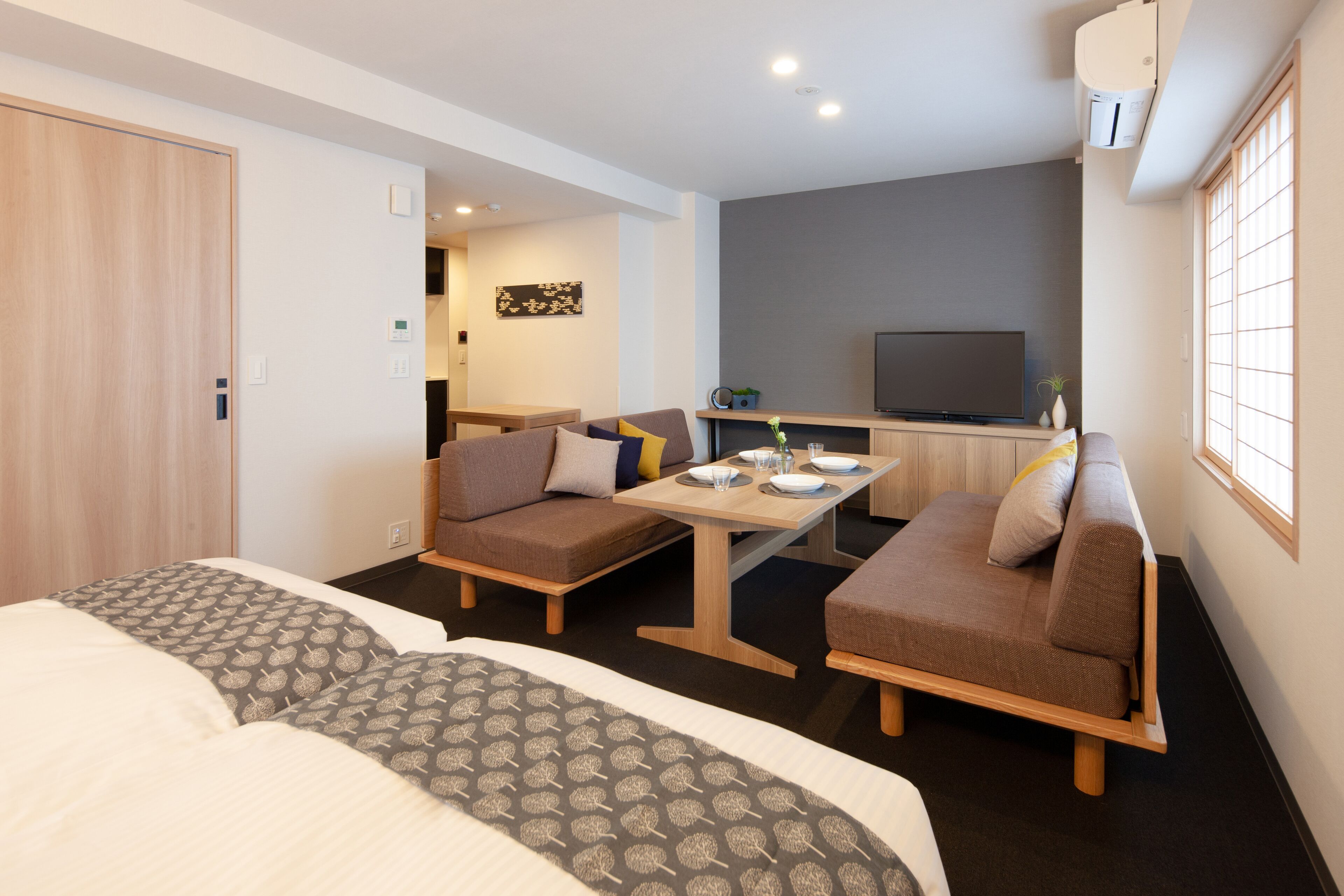 Quarto de hotel moderno com dois sofás, uma mesa de jantar e uma televisão.