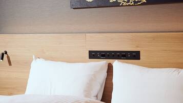A hotel room with a wooden headboard, a power strip with multiple outlets, and a wall-mounted artwork.
