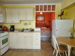 Enjoy a compact space with a kitchenette, dining area, and a cozy bedroom featuring a bed and nightstand.