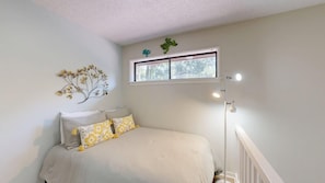 A bedroom with a bed, a window, and a wall-mounted decoration. - Short walk or bike ride to the beach and Palmetto Dunes golf! (Hilton Head)