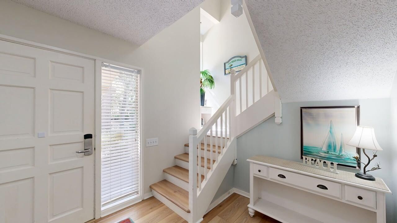 A staircase with white railings leading to a landing, a white console table with drawers, and a framed picture on the wall.