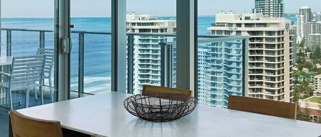 A dining area with a view of the ocean and cityscape.
