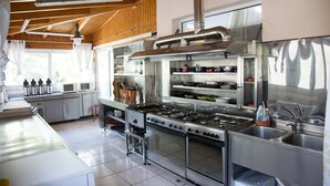 Una cocina moderna con electrodomésticos de acero inoxidable, vigas de techo de madera y un amplio ventanal que proporciona luz natural.