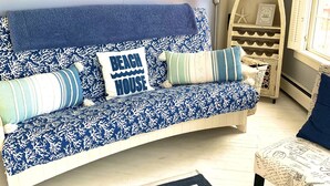 Una habitación con un sofá de diseño azul y blanco, una decoración con forma de estrella de mar y una estantería de madera con un letrero de temática playera.
