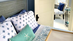 Un dormitorio con una cama, una puerta que da a otra habitación y un letrero en la pared.