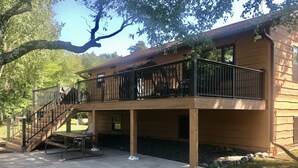 A two-story wooden house with a balcony, outdoor seating, and a stone pathway.