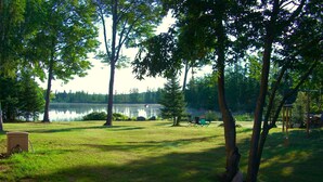 A grassy area with a lake, trees, and a gazebo.