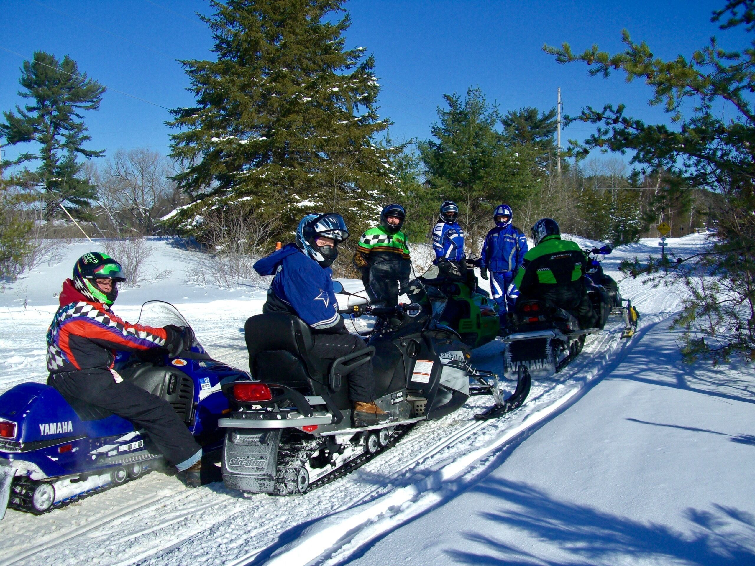 A group of people on snowmobiles on a snowy path.