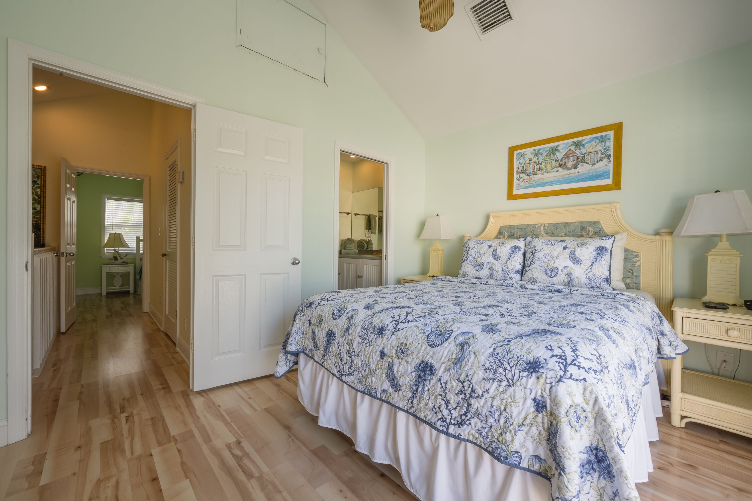 A bedroom with a large bed, a nightstand, a lamp, and a painting on the wall.