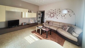 Ein modernes Wohnzimmer mit einer Couch, einem Couchtisch, einem Fernseher und Wanddekoration.