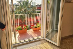 A sliding glass door leading to a balcony with potted plants and a metal railing.